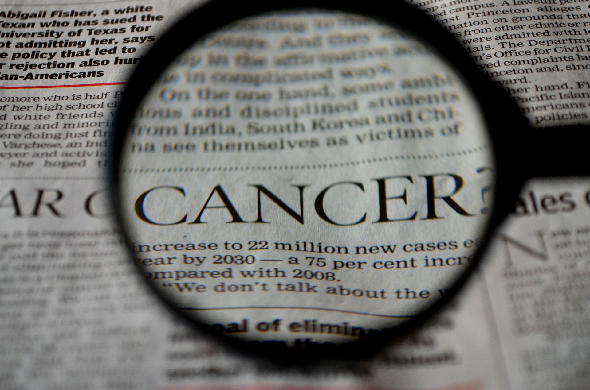 Vergrößerter Zeitungsartikel über Brustkrebs unter der Lupe. Bild zum Thema: Brustimplantate und Krebs: Die ganze Wahrheit