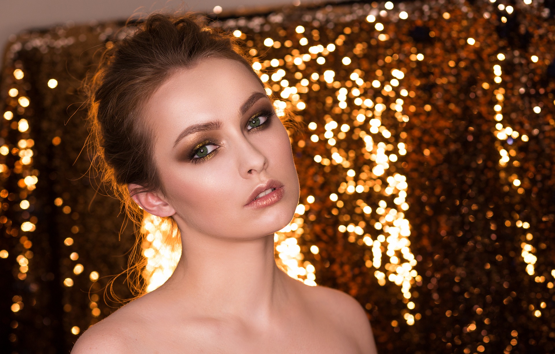 toll aussehendes junges Mädchen mit perfektem Make-up und goldenen Lichtern im Hintergrund. Bild zum Thema: Rich Girl Face – Der Beauty-Trend 2020!