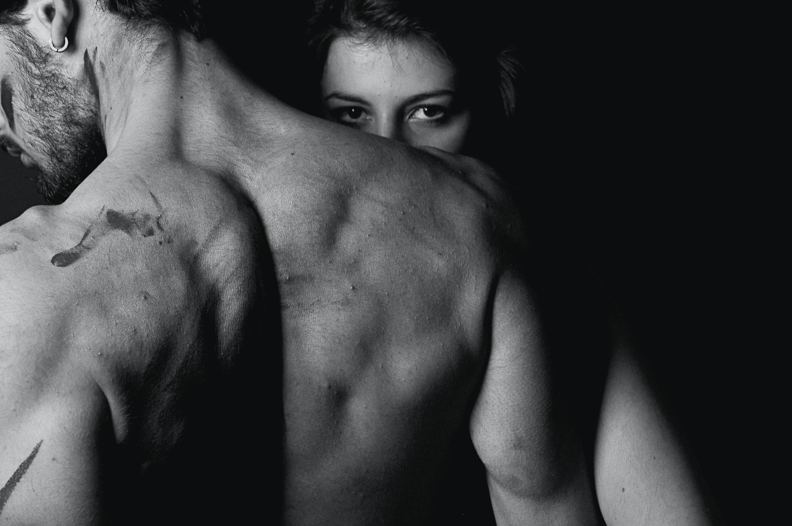 Rücken eines muskulösen Mannes, der nach links schaut. Die Frau blickt über seine Schulter - Bild zum Thema Typisch männliche Eingriffe